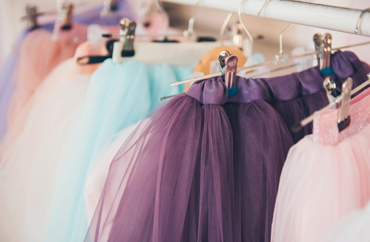 Clothing for a little girl on a clothes rack in a wardrobe. Fash