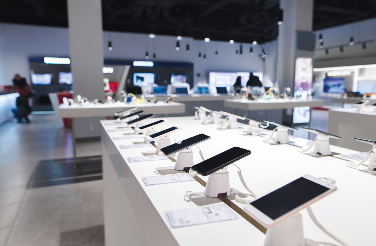 Many smartphones are on the table in the technology store. Buying a mobile phone at the electronics store. Smartphones on the background of the store